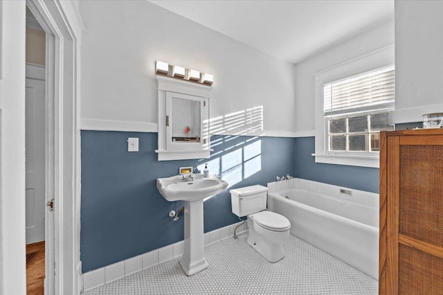 bathroom with a bathing tub, tile patterned floors, and toilet