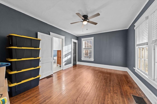 unfurnished bedroom with multiple windows, wood-type flooring, ornamental molding, and ceiling fan