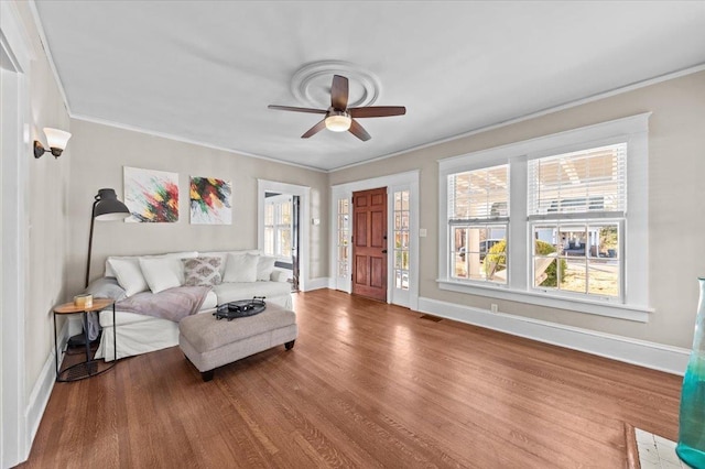 living room featuring crown molding, ceiling fan, and wood-type flooring