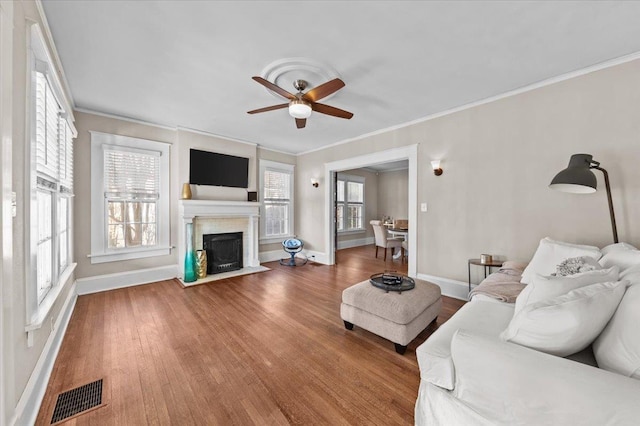 living room with ceiling fan, ornamental molding, a healthy amount of sunlight, and hardwood / wood-style floors