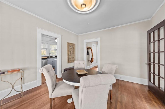 dining area featuring hardwood / wood-style flooring, crown molding, and sink