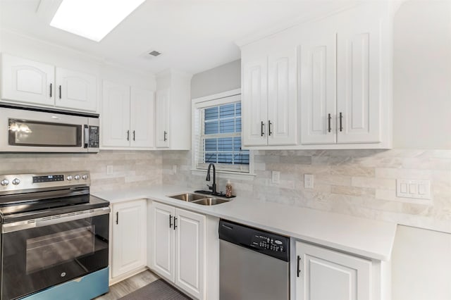 kitchen featuring sink, white cabinetry, stainless steel appliances, tasteful backsplash, and light hardwood / wood-style floors