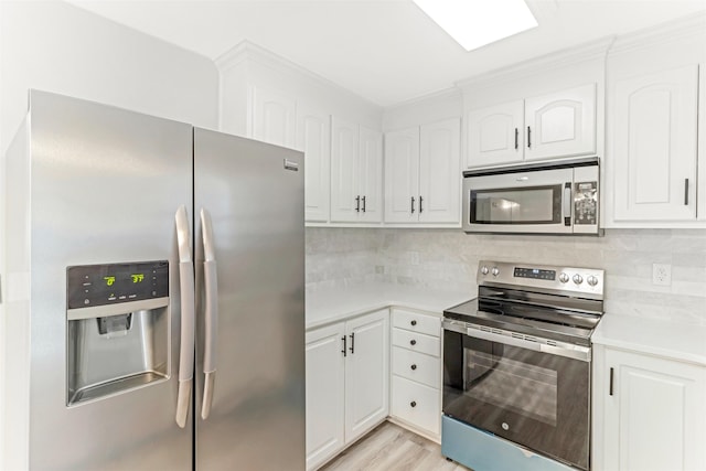 kitchen featuring stainless steel appliances, white cabinetry, tasteful backsplash, and light hardwood / wood-style floors