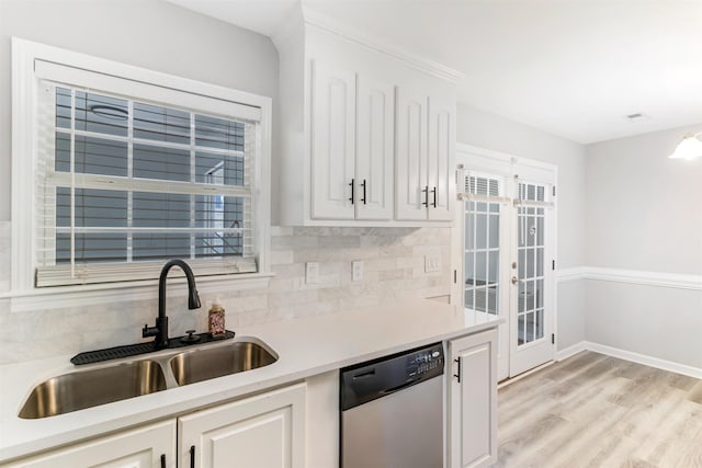 kitchen with sink, white cabinets, backsplash, stainless steel dishwasher, and light hardwood / wood-style floors