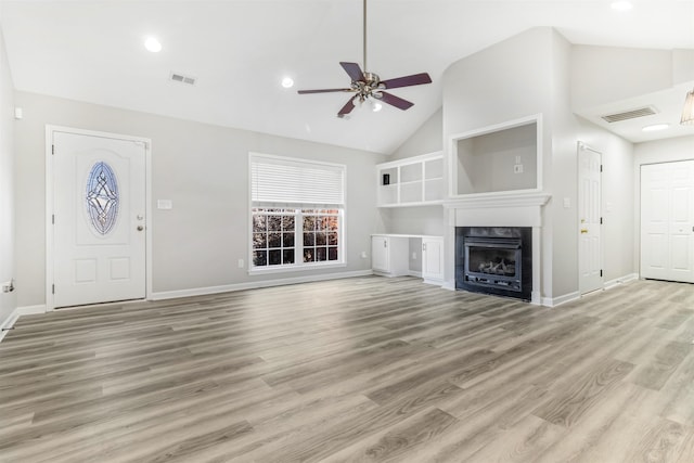 unfurnished living room featuring a tiled fireplace, ceiling fan, light wood-type flooring, and high vaulted ceiling