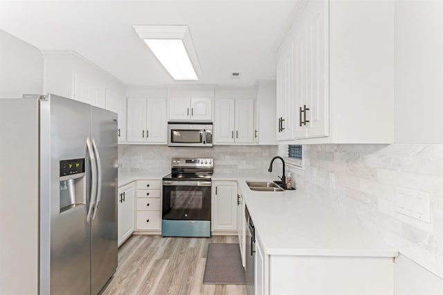 kitchen featuring sink, white cabinetry, tasteful backsplash, light hardwood / wood-style flooring, and appliances with stainless steel finishes