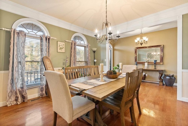 dining area featuring an inviting chandelier, ornamental molding, and light wood-type flooring