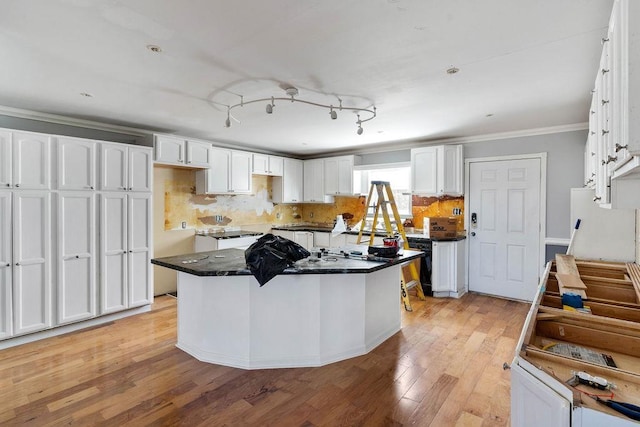 kitchen featuring a kitchen island, tasteful backsplash, white cabinetry, ornamental molding, and light wood-type flooring