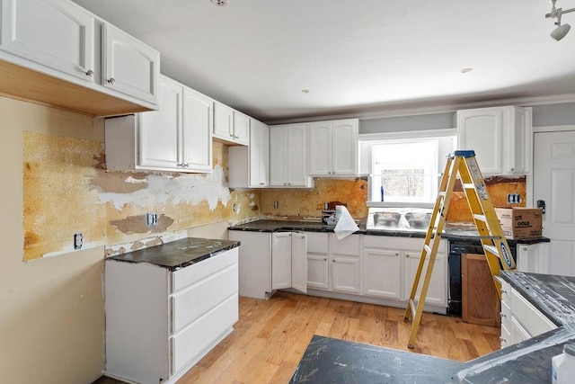 kitchen with white cabinetry, backsplash, and light wood-type flooring