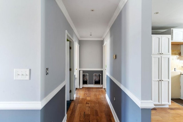 corridor with ornamental molding and light wood-type flooring