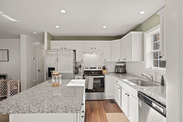 kitchen with white cabinetry, appliances with stainless steel finishes, sink, and a kitchen island