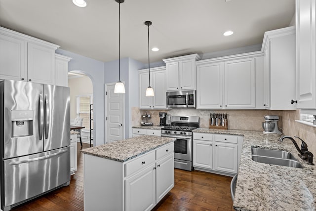 kitchen featuring appliances with stainless steel finishes, pendant lighting, white cabinetry, sink, and light stone counters