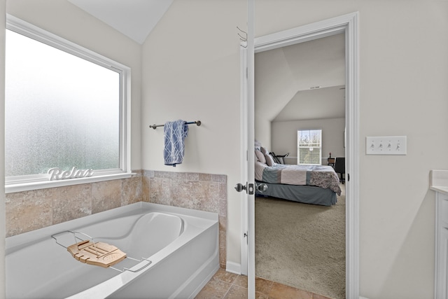 bathroom with vanity, a tub to relax in, and vaulted ceiling