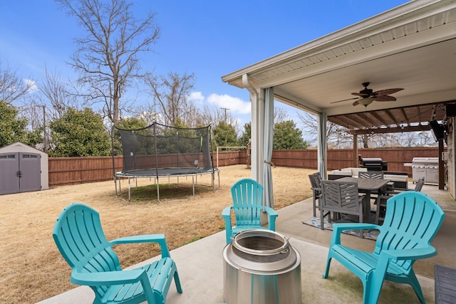 view of patio featuring a trampoline, a grill, and a storage unit