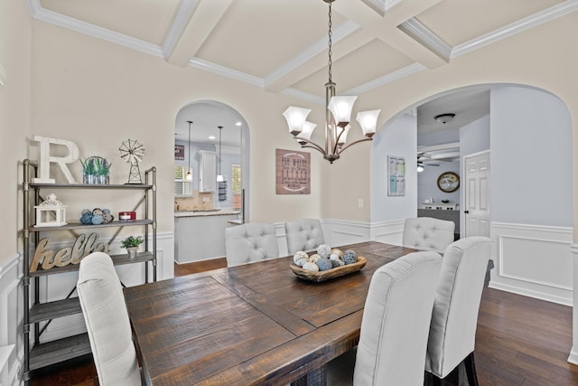 dining room featuring ceiling fan with notable chandelier, coffered ceiling, crown molding, dark wood-type flooring, and beam ceiling