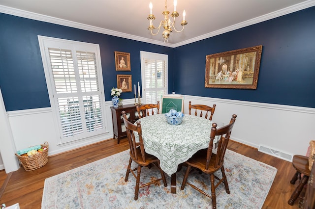 dining space featuring an inviting chandelier, hardwood / wood-style floors, and crown molding