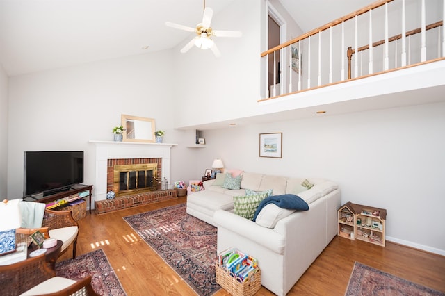 living room featuring hardwood / wood-style flooring, ceiling fan, high vaulted ceiling, and a fireplace