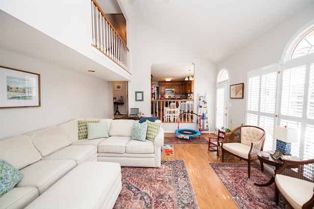 living room featuring high vaulted ceiling and light wood-type flooring