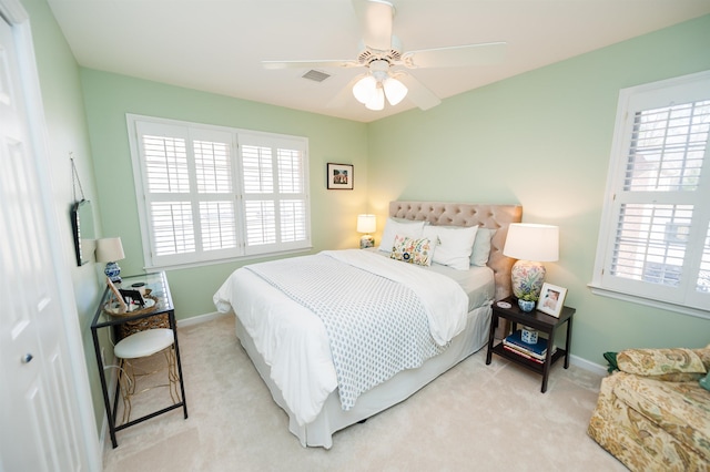 bedroom with ceiling fan, multiple windows, and light carpet