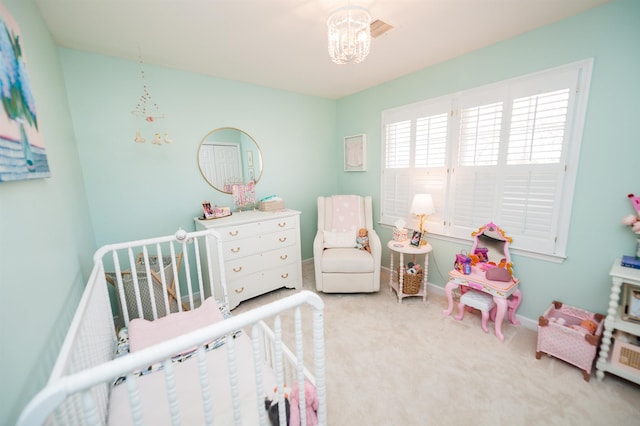 bedroom featuring an inviting chandelier, carpet, and a crib