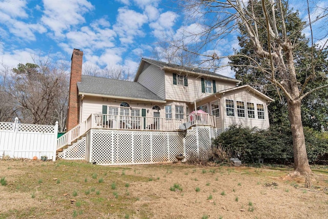 back of house with a wooden deck, a sunroom, and a lawn