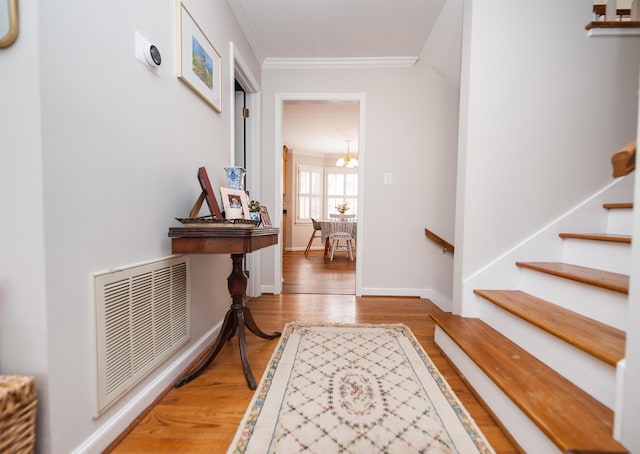 entryway featuring hardwood / wood-style floors, crown molding, and a notable chandelier