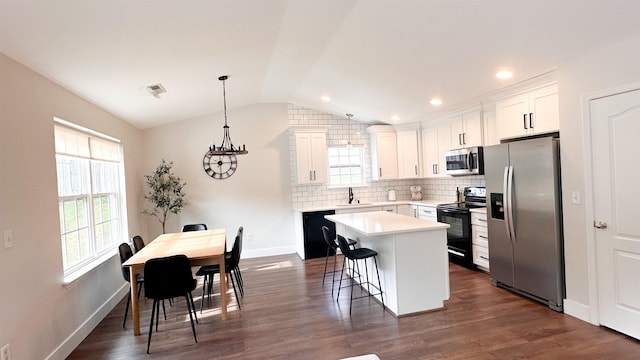 kitchen with a breakfast bar, white cabinetry, a center island, hanging light fixtures, and black appliances