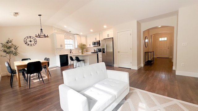 living room featuring sink, dark hardwood / wood-style floors, a chandelier, and vaulted ceiling