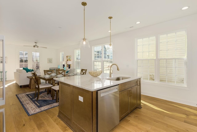 kitchen with decorative light fixtures, dishwasher, an island with sink, sink, and light hardwood / wood-style floors