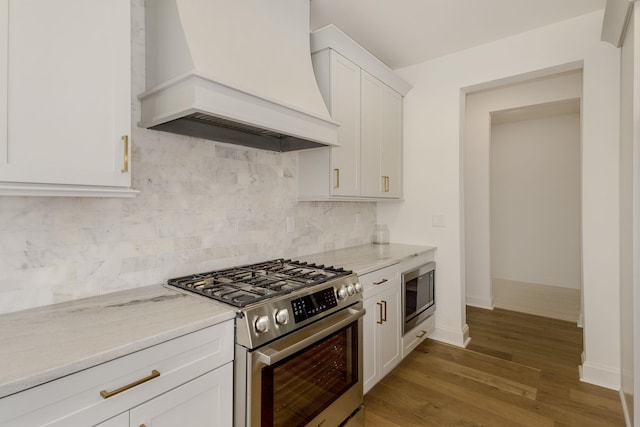 kitchen with appliances with stainless steel finishes, white cabinets, backsplash, custom exhaust hood, and dark wood-type flooring