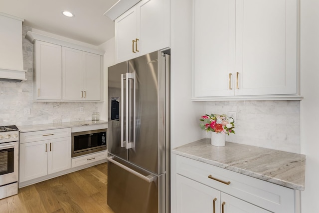 kitchen featuring white gas range oven, white cabinetry, high quality fridge, built in microwave, and light wood-type flooring