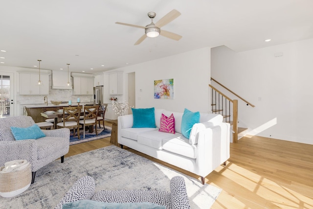 living room featuring ceiling fan, sink, and light hardwood / wood-style flooring