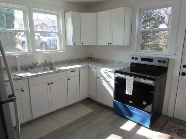 kitchen featuring white cabinetry, sink, stainless steel range with electric cooktop, and light hardwood / wood-style floors