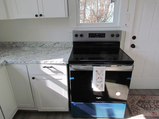 kitchen with light stone counters, white cabinetry, and stainless steel electric range