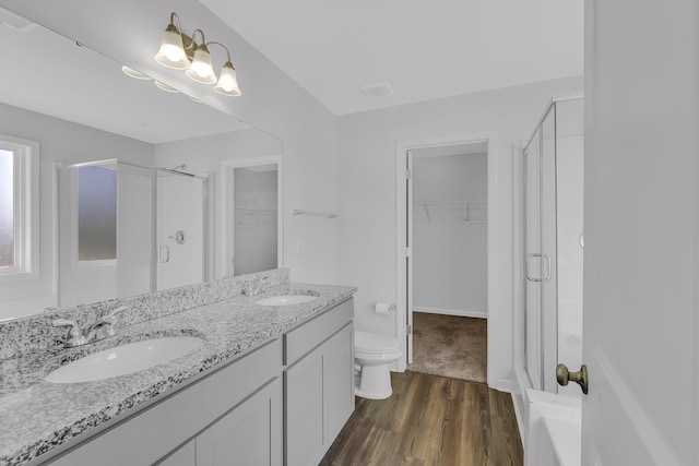 bathroom with hardwood / wood-style flooring, vanity, toilet, and walk in shower