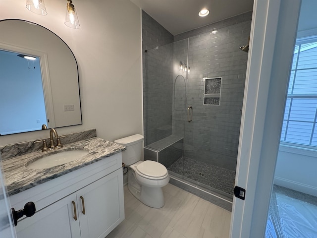 bathroom featuring vanity, toilet, and a shower with shower door