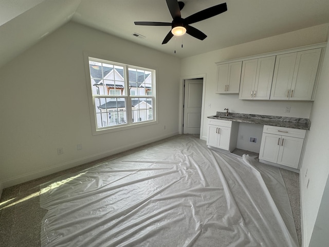 kitchen with built in desk, white cabinetry, lofted ceiling, sink, and ceiling fan