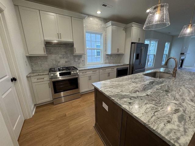 kitchen featuring white cabinetry, appliances with stainless steel finishes, sink, and decorative light fixtures