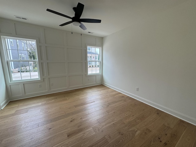 spare room featuring a wealth of natural light, light hardwood / wood-style flooring, and ceiling fan