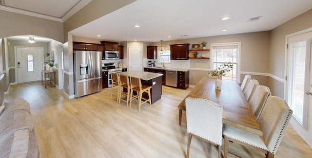 dining room with crown molding, sink, and light wood-type flooring