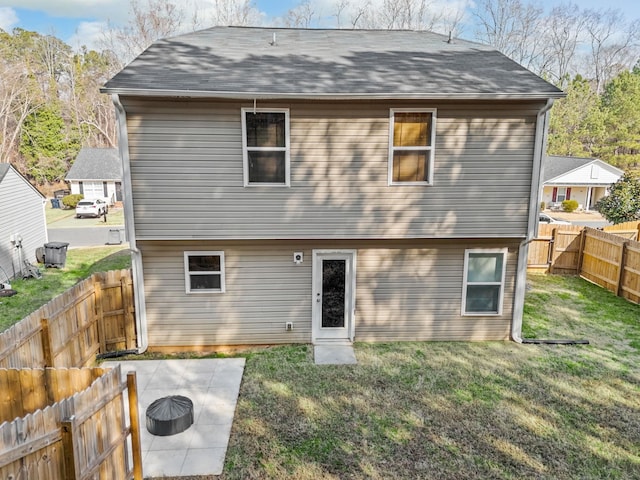 rear view of property featuring a lawn and an outdoor fire pit