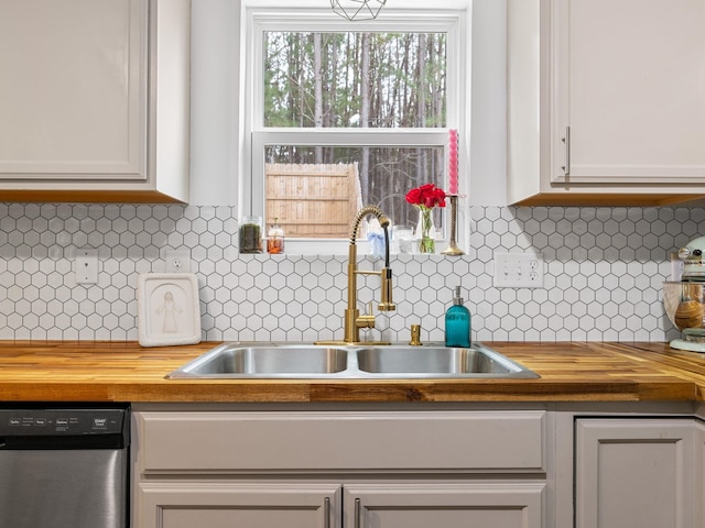 kitchen featuring white cabinetry, sink, dishwasher, and butcher block countertops