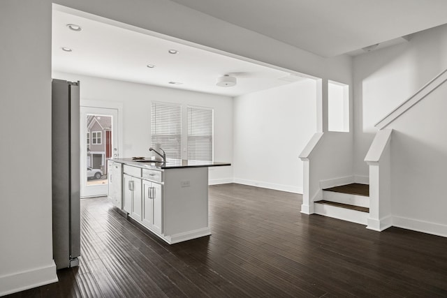 kitchen featuring stainless steel refrigerator, sink, white cabinets, dark hardwood / wood-style flooring, and a kitchen island with sink