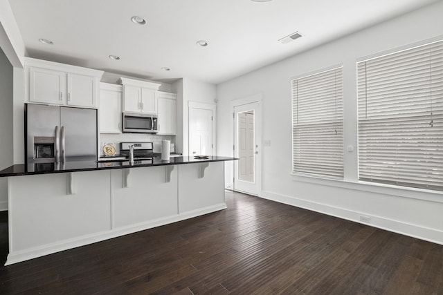 kitchen with dark wood-type flooring, a kitchen bar, sink, appliances with stainless steel finishes, and white cabinets