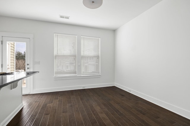 unfurnished dining area featuring dark wood-type flooring