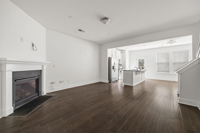 unfurnished living room featuring dark hardwood / wood-style floors and sink