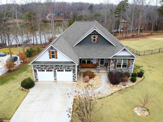 craftsman-style house featuring a garage, a water view, covered porch, and a front lawn