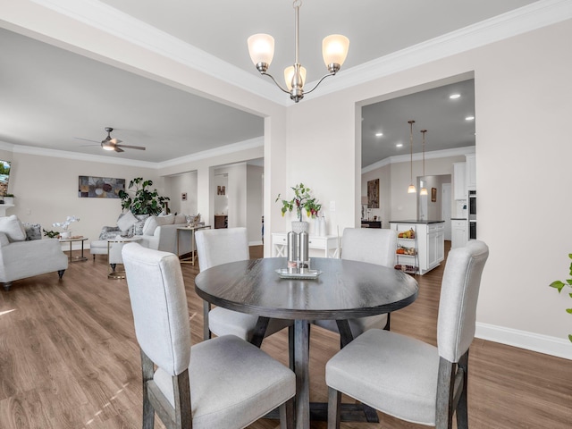 dining area featuring wood-type flooring, ceiling fan with notable chandelier, and crown molding