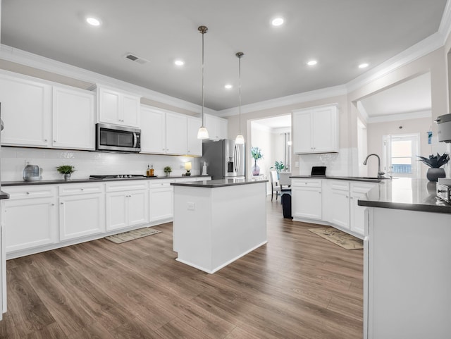 kitchen with appliances with stainless steel finishes, sink, white cabinets, and decorative light fixtures