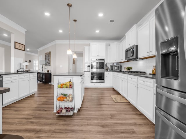 kitchen with stainless steel appliances, decorative light fixtures, and white cabinets